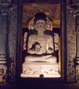 Large seated Buddha in a small room, carved from solid rock at Ajanta caves.