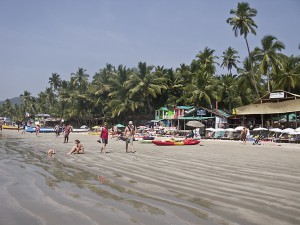 Sunbathers, beach walkers and restaurants line Palolem Beach, Goa, India.