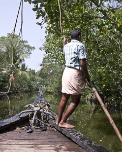 A boatman pushes a houseboat along a backwater canal in Kerala.